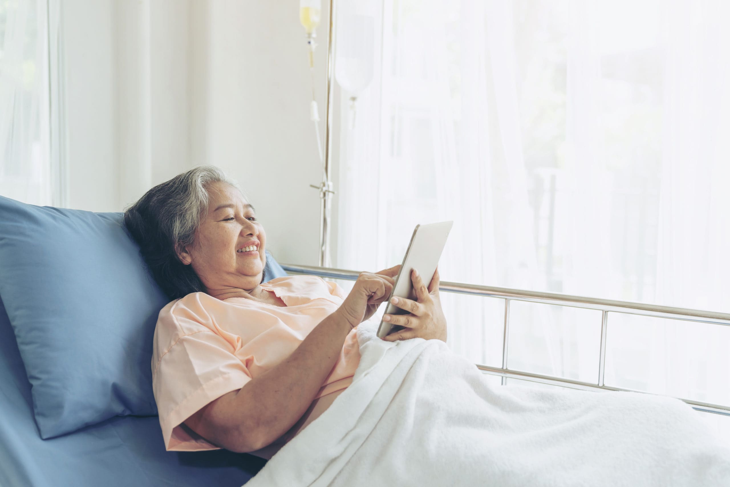 Elderly senior woman patients in hospital bed patients using smart phone call to descendant relatives feel happiness